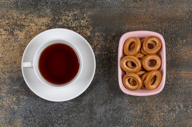 Schüssel Cracker und Tasse Tee auf Marmor.