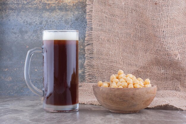 Schüssel Erbsen und Glas dunkles Bier auf Marmortisch. Foto in hoher Qualität