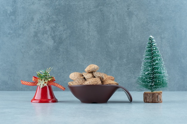 Schüssel geschälte Mandeln und Weihnachtsdekorationen auf Marmor.