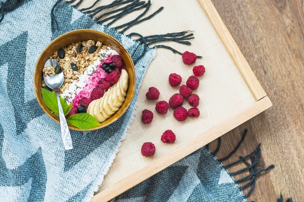 Schüssel Hafermehl mit Himbeeren und Bananenscheibe auf Tablett