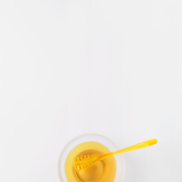 Schüssel Honig mit Schöpflöffel auf weißer Oberfläche
