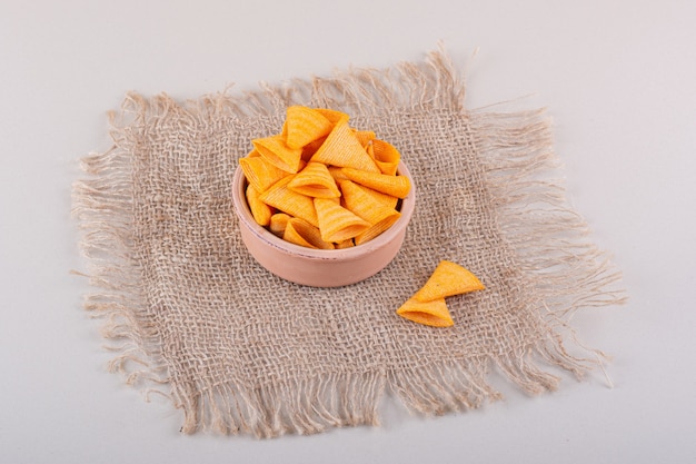 Schüssel mit dreieckigen knusprigen Chips auf Marmorhintergrund. Foto in hoher Qualität