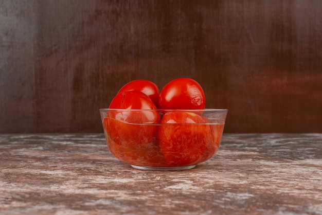 Schüssel mit eingelegten Tomaten auf Marmoroberfläche.