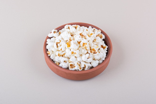 Schüssel mit gesalzenem Popcorn für Filmabend auf weißem Hintergrund. Foto in hoher Qualität