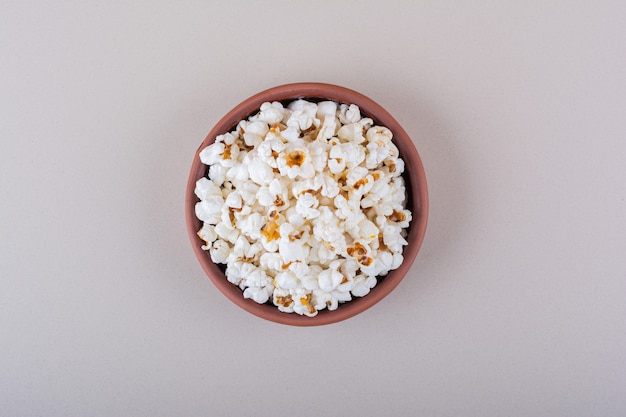 Schüssel mit gesalzenem Popcorn für Filmabend auf weißem Hintergrund. Foto in hoher Qualität