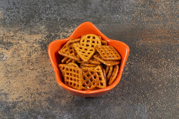 Schüssel mit gesalzenen Crackern auf Marmoroberfläche.