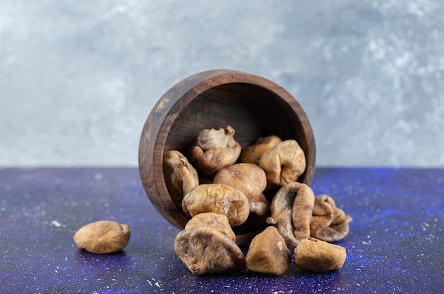 Schüssel mit getrockneten Feigen auf blauem Tisch.