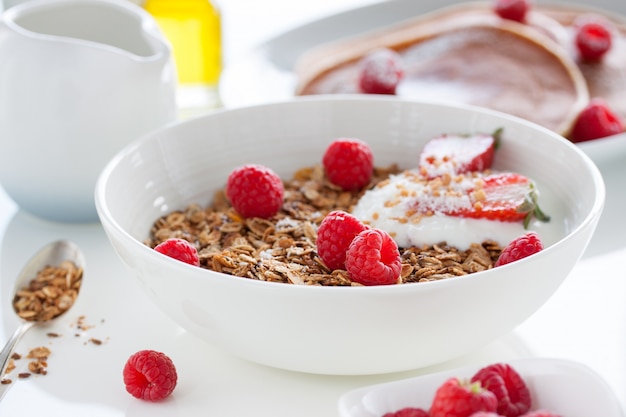 Schüssel mit Joghurt, Müsli und Himbeeren