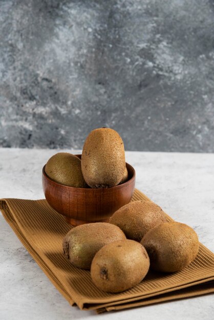 Schüssel mit leckeren Kiwis auf brauner Tischdecke