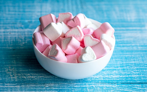 Kostenloses Foto schüssel mit marshmallows in form von herzen auf blauem holzhintergrund