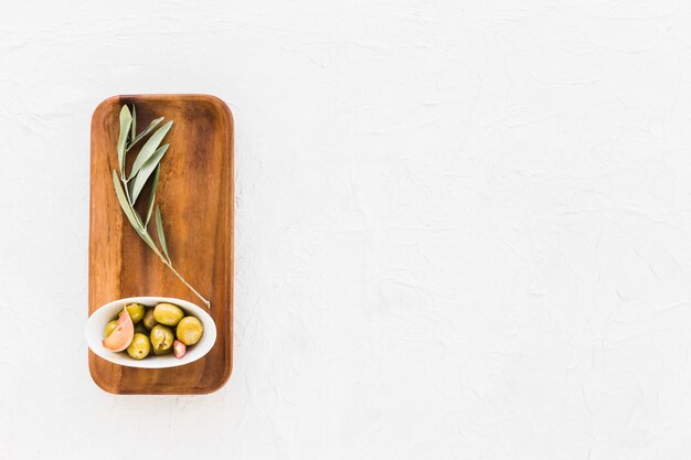 Schüssel Oliven mit dem Zweig auf hölzernem Brett über dem weißen Hintergrund