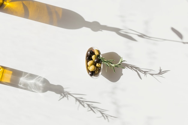 Schüssel Oliven mit Schatten der Ölflasche auf weißem Hintergrund