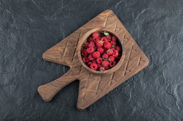 Schüssel reife Himbeeren auf Holzbrett.