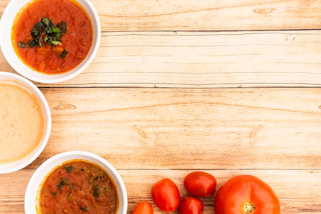 Schüssel Soßen und frische Tomaten auf Holztisch