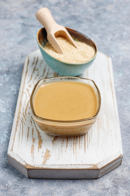 Schüssel Tahini mit Samen des indischen Sesams auf Betondecke