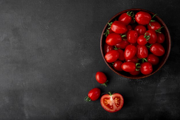 Schüssel Tomaten auf der rechten Seite auf schwarzer Oberfläche