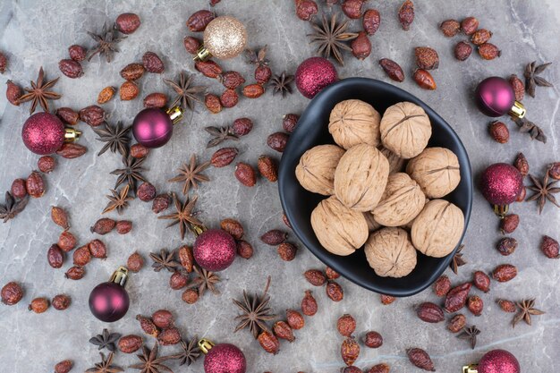 Schüssel Walnüsse mit Hagebutten und Weihnachtskugeln.