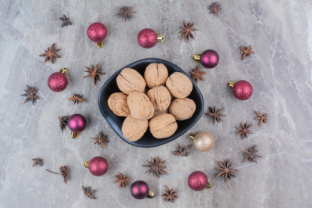 Schüssel Walnüsse mit Nelken und Weihnachtskugeln.