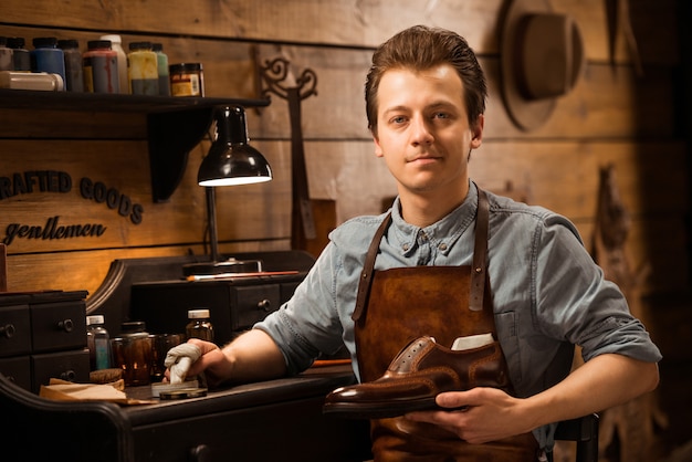 Schuhmacher in der Werkstatt, die Schuhe hält