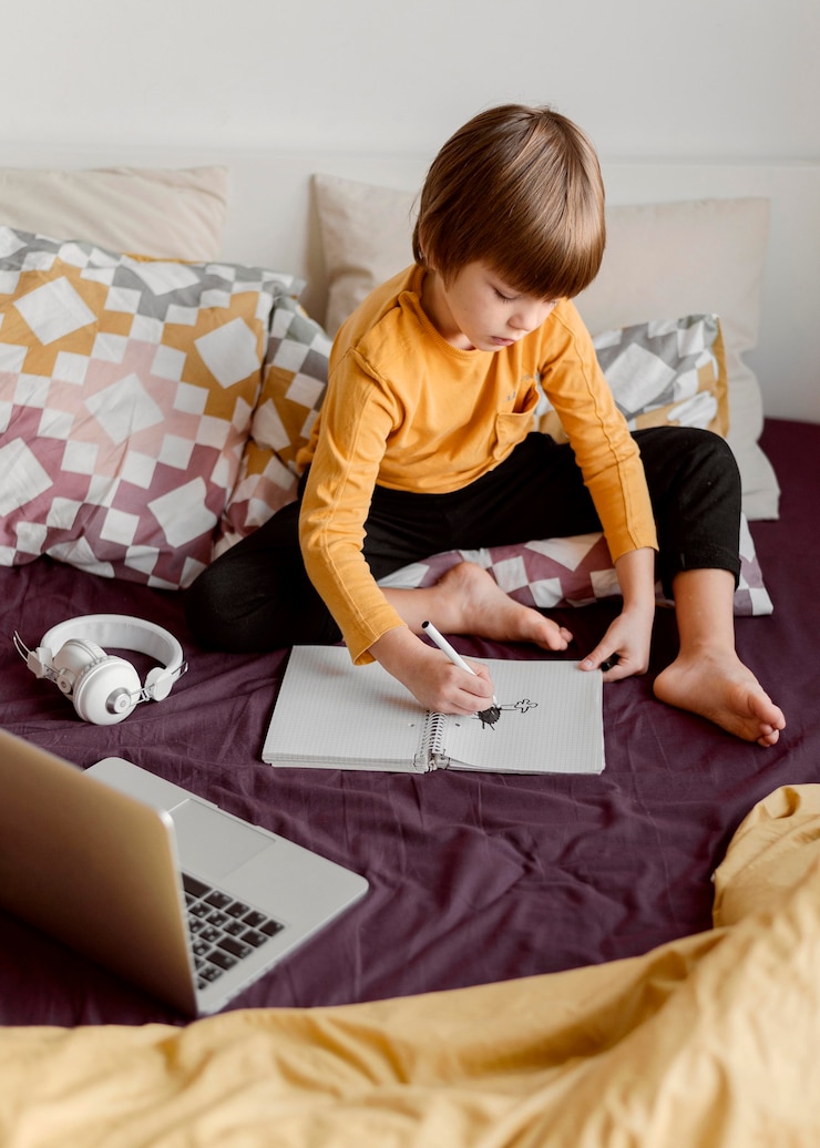 Kostenlose Foto schuljunge sitzt im bett und lernt