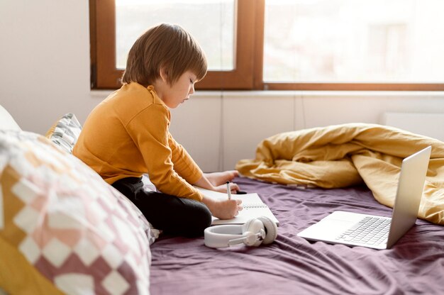 Schuljunge sitzt seitlich im Bett