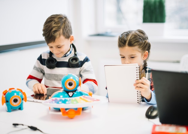 Schulkinder sind damit beschäftigt, Notizen zu schreiben und digitale Tablets in der Klasse zu verwenden