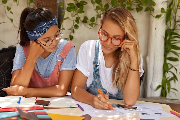 Schulmädchen bereiten sich auf wichtige prüfungen am college vor und unterstreichen informationen für die kursarbeit