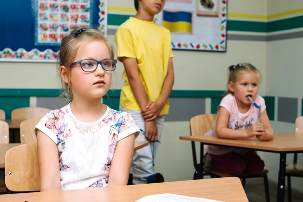 Schulmädchen in Gläser sitzen am Schreibtisch