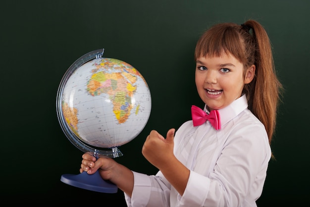 Schulmädchen mit globus zeigt ok zeichen