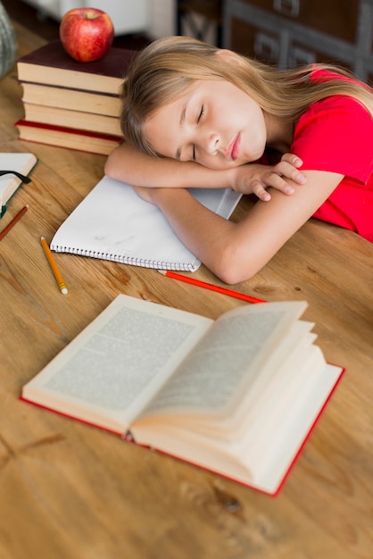 Kostenloses Foto schulmädchen schläft inmitten von lehrbüchern