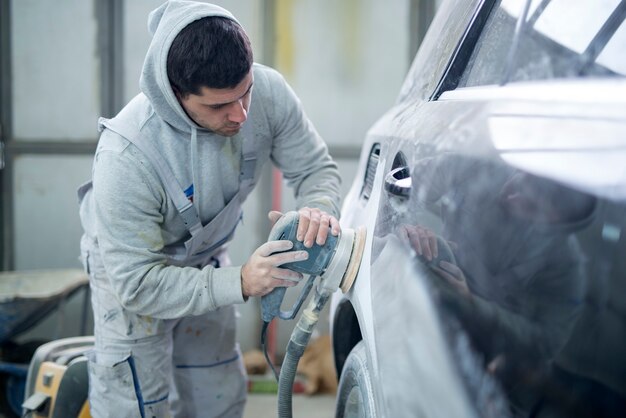 Schuss des professionellen Reparaturmanns, der Fahrzeug für neuen Lack vorbereitet