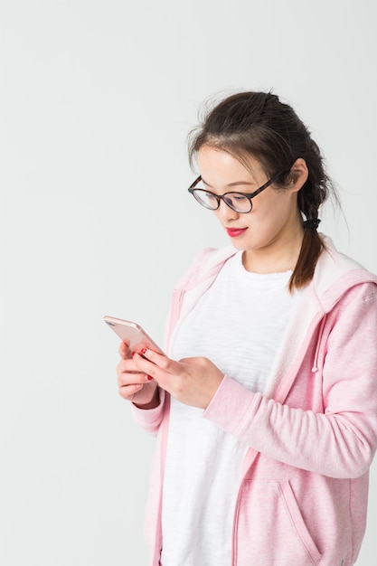 Schuss im Studio der jungen asiatischen Frau Handy spielen