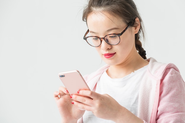 Schuss im Studio der jungen asiatischen Frau, um Handy-Selbst-Timer zu spielen