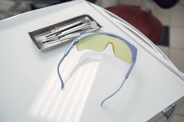 Schutzbrille in der Zahnarztpraxis. Die Werkzeuge liegen auf einem Tablett. Vorbereitung des Zahnarztes vor der Aufnahme