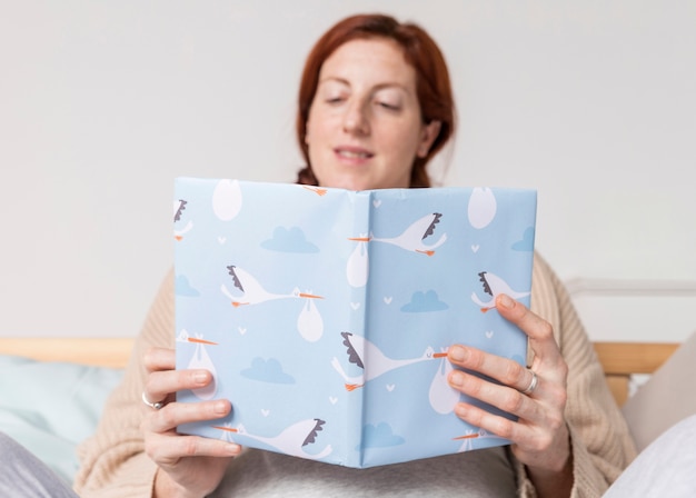 Schwache Frau des niedrigen Winkels, die Babybücher liest