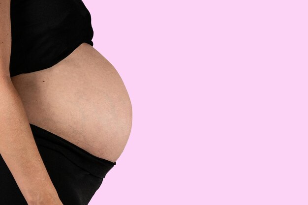 Schwangere Frau auf rosa Hintergrund Kopieren Sie Platz