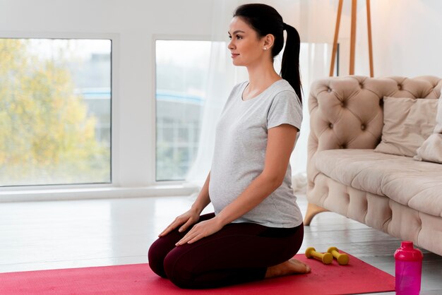 Schwangere Frau der Seitenansicht, die Yoga tut