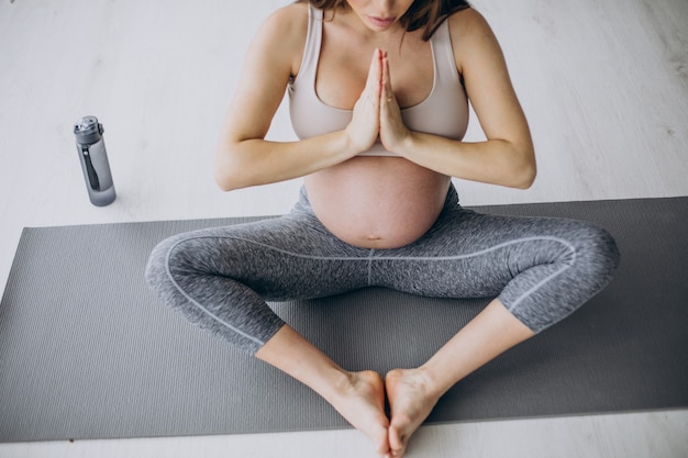 Kostenloses Foto schwangere frau, die zu hause yoga auf der matte praktiziert