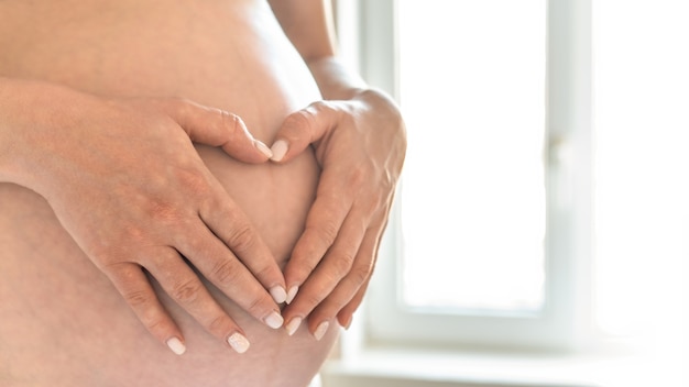 Schwangere Frau hält ihren nackten Bauch