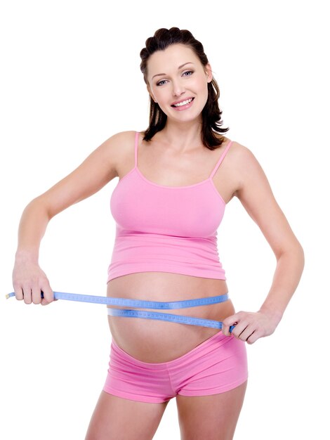 schwangere Frau misst ihren Bauch mit Maßband