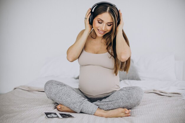 Schwangere Frau mit Ultraschallfoto beim Musikhören