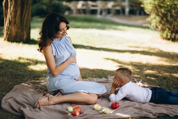 Schwangere Frau und ihr kleiner Sohn, die Picknick im Park haben