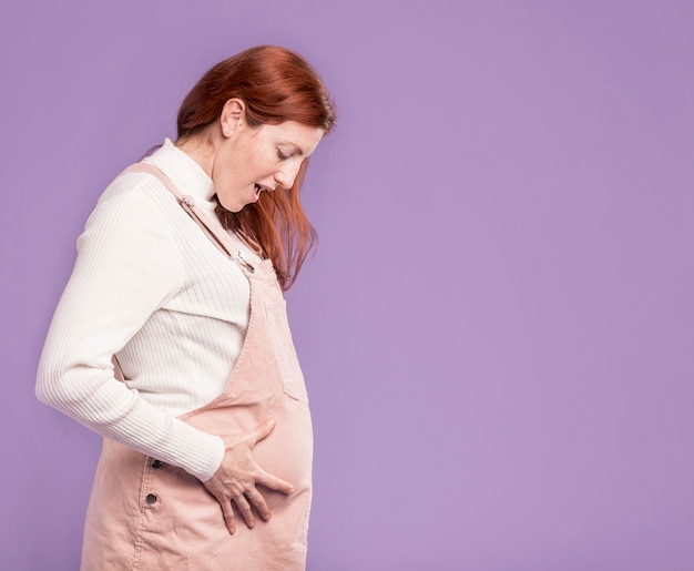Schwangere Frau von der Seitenansicht überrascht von ihrem Bauch