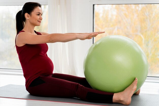 Schwangere junge Frau, die mit Fitnessball trainiert
