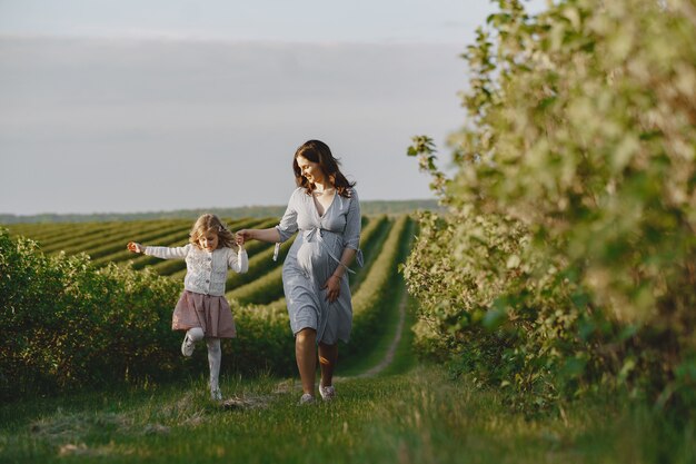 Schwangere Mutter mit ihrer Tochter auf einem Feld