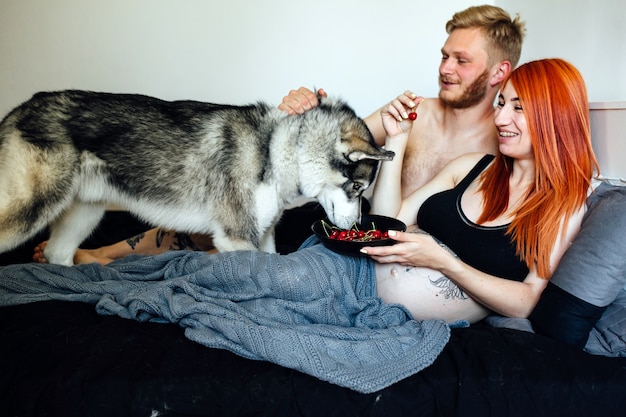 Schwangere Paar mit Hund auf dem Bett