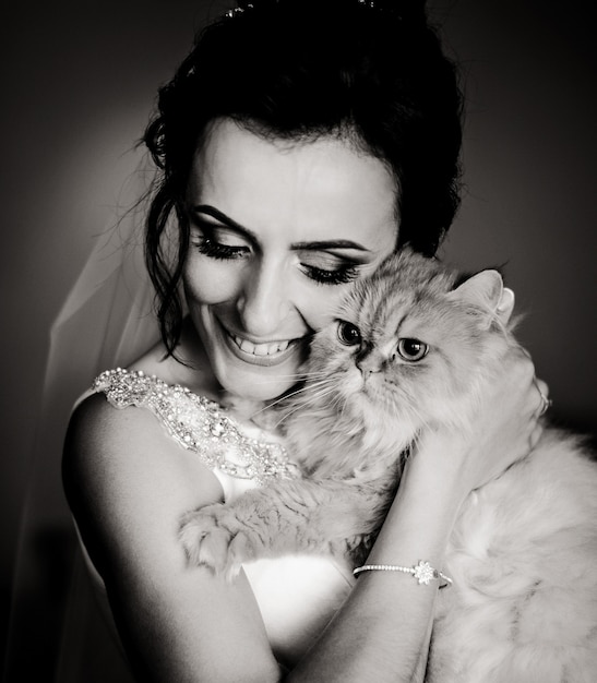 Schwarz-Weiß-Bild der glücklichen Braut halten flauschige Katze hinter ihrem Gesicht