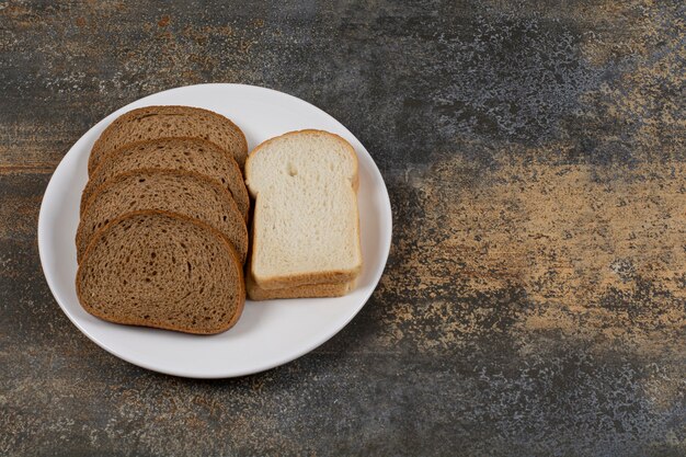 Schwarz-Weiß-Brotscheiben auf weißem Teller.