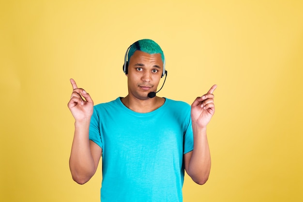 Schwarzafrikanischer Mann im lässigen auf gelbem Wandblauhaar-Callcenter-Arbeiter glücklicher Kundenbetreuungsbetreiber mit Kopfhörern zeigen Finger nach oben