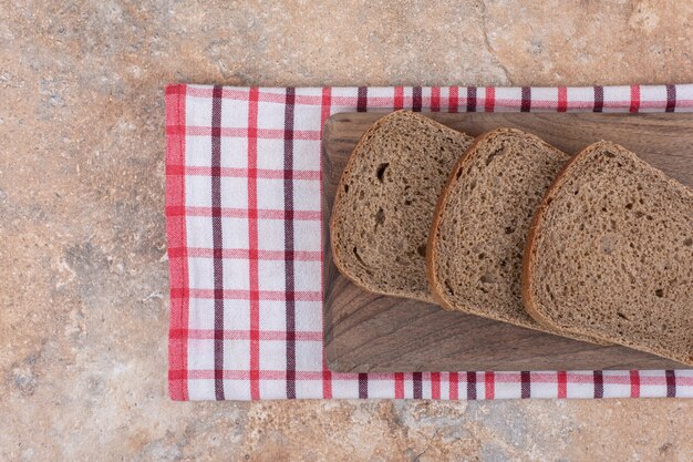 Schwarzbrotscheiben auf Holzbrett mit Tischdecke